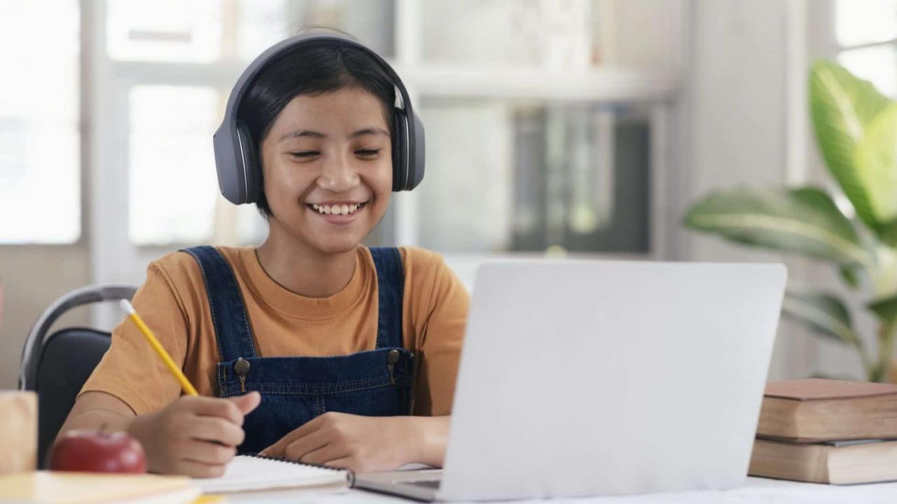 Happy asian girl learning online at home