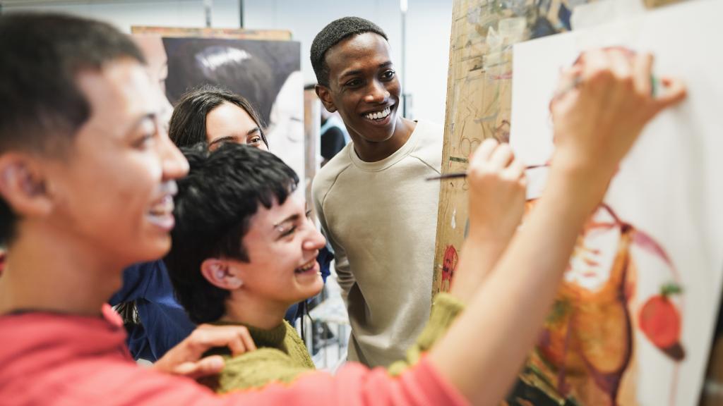Multiracial students painting inside art room class at school
